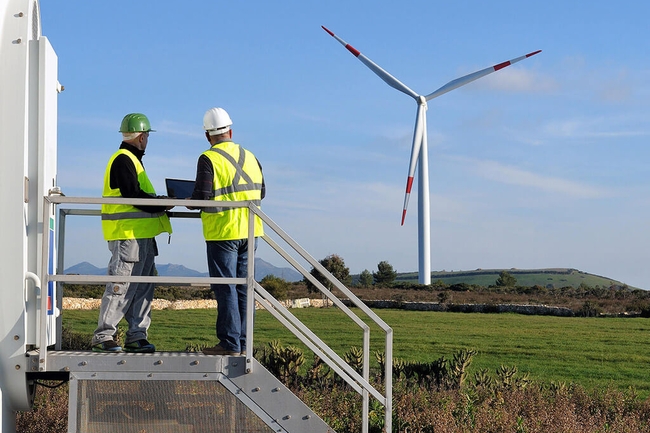 Zwei Ingenieure stehen auf einem Feld mit Windkraftanlage
