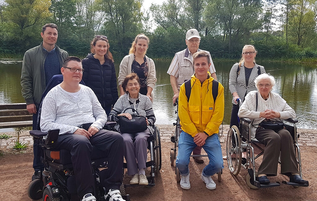 Prognos Mitarbeiterinnen und Mitarbeiter mit Bewohnern und Bewohnerinnen eines Pflegeheimes im Park