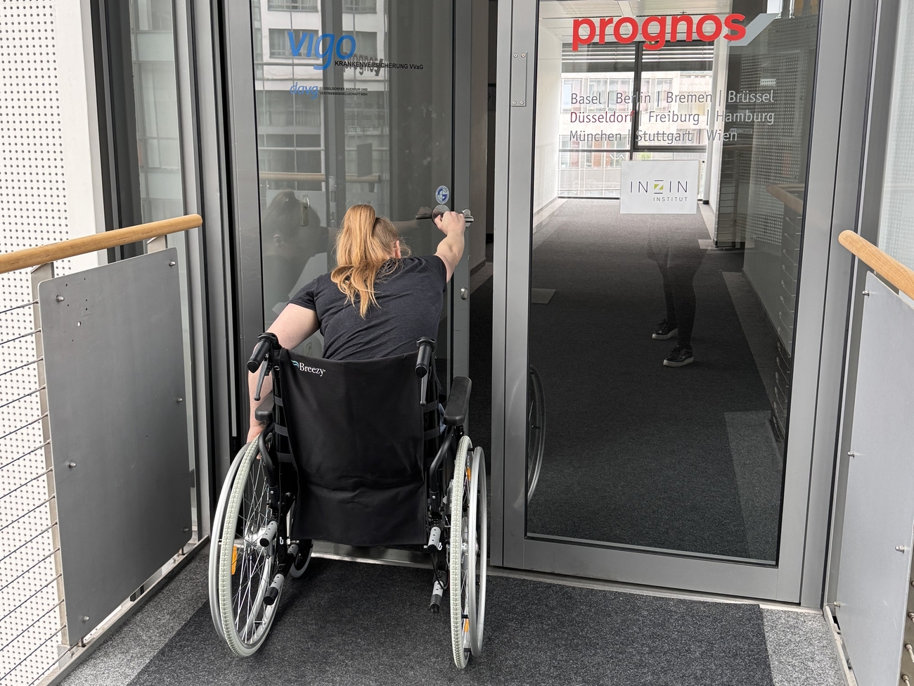 Mitarbeiterin im Rollstuhl öffnet Haustür