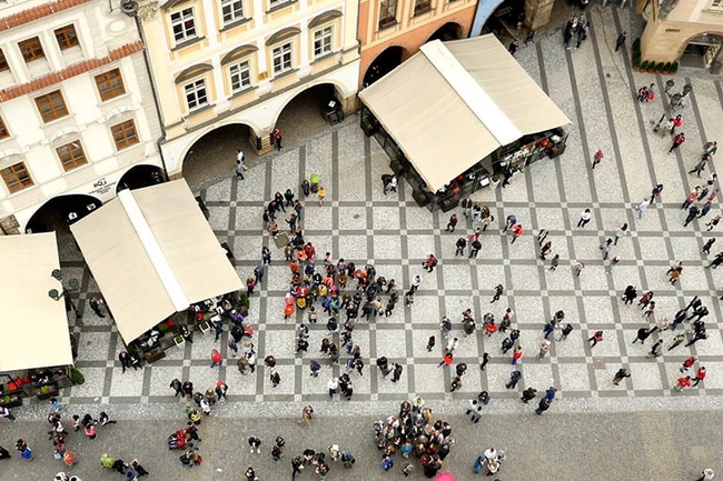 Viele Personen laufen auf einem Marktplatz. Von oben fotografiert. 