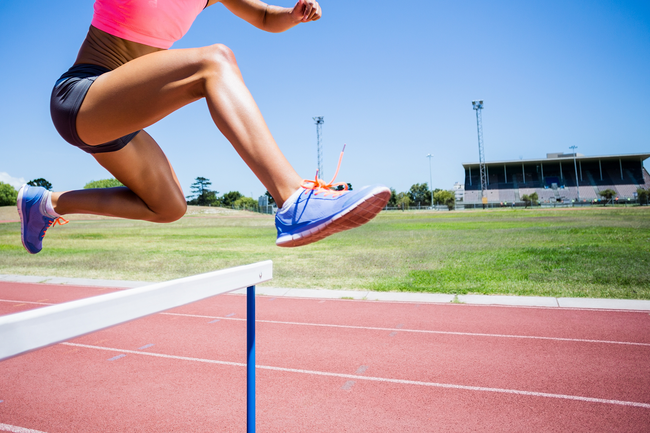 Sportlerin springt über eine Hürde