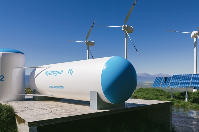 Wasserstofftanks sind im Vordergrund zu sehen. Im Hintergrund stehen drei Windräter und PV-Anlagen