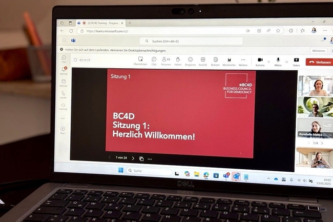 Ein Bildschirm auf einem Schreibtisch zeigt die Startfolie der BC4D-Schulungsreihe 