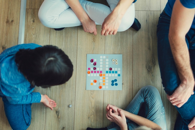 Eine Familie sitzt auf dem Boden und spielt ein Gesellschaftsspiel 