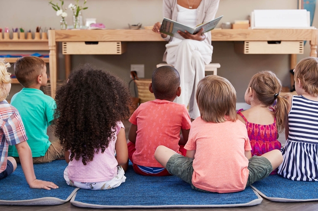 Kindergärtnerin liest Kindern ein Buch vor 