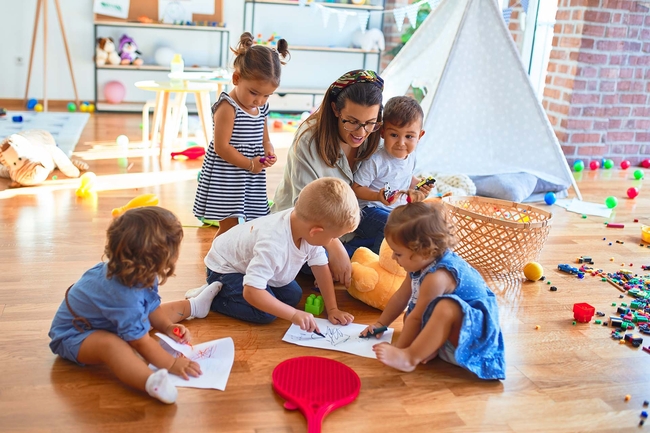 Kindergärtnerin liest Kindern ein Buch vor 