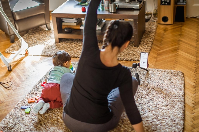Frau mit Kind sitzt auf dem Boden und macht Sportübungen