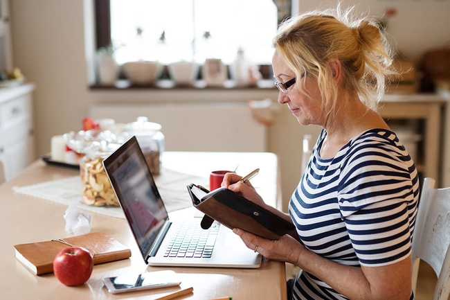 Ältere Frau mit Laptop, arbeiten am Küchentisch