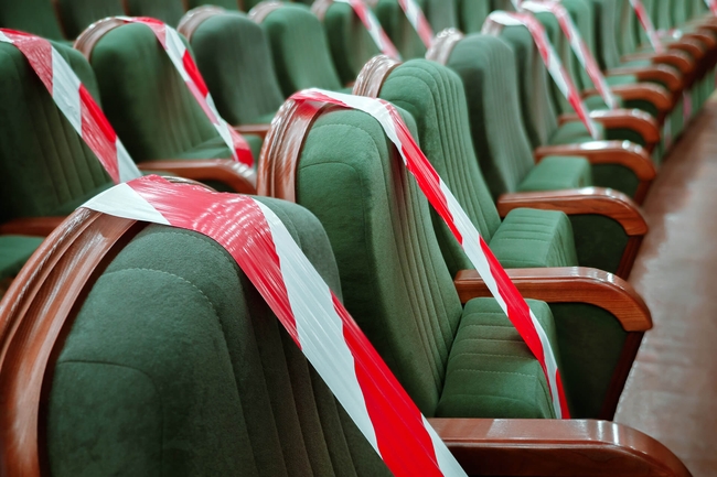Leerer Theatersaal. Sitze sind mit rot/weißem Absperrband umwickelt.