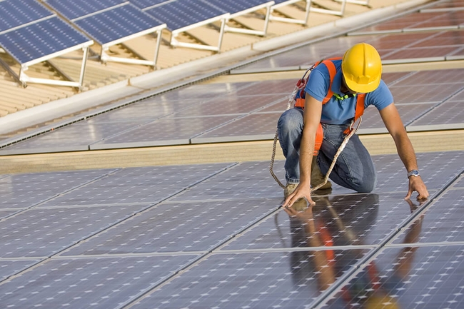Ein Arbeiter legt Solarpanele auf ein Dach