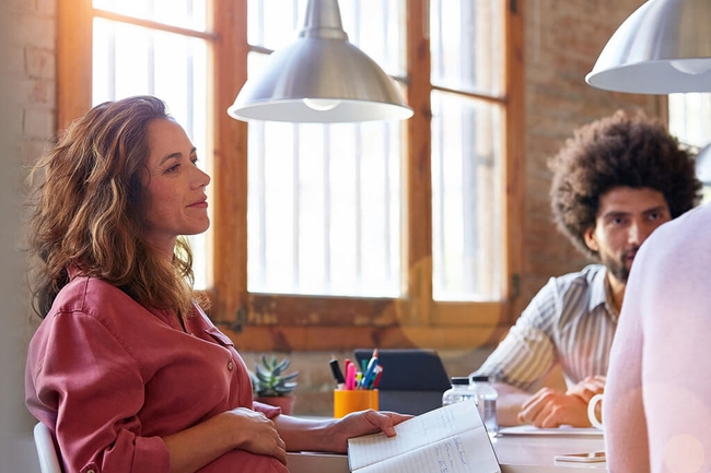 Schwangere Frau sitzt im Business-Meeting