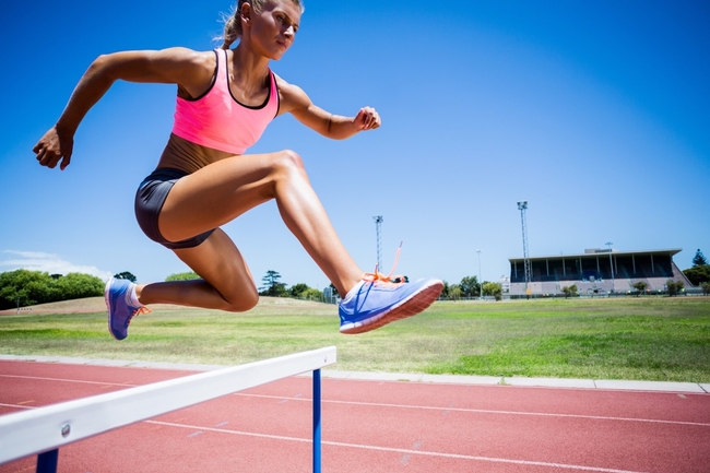 Sportlerin springt über eine Hürde