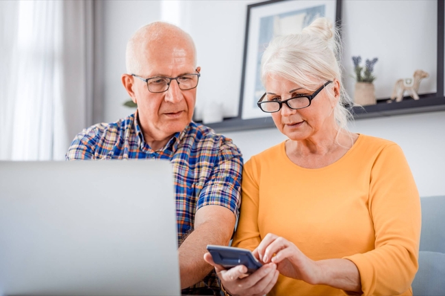 Zwei Senioren benutzen Laptop und Smartphone