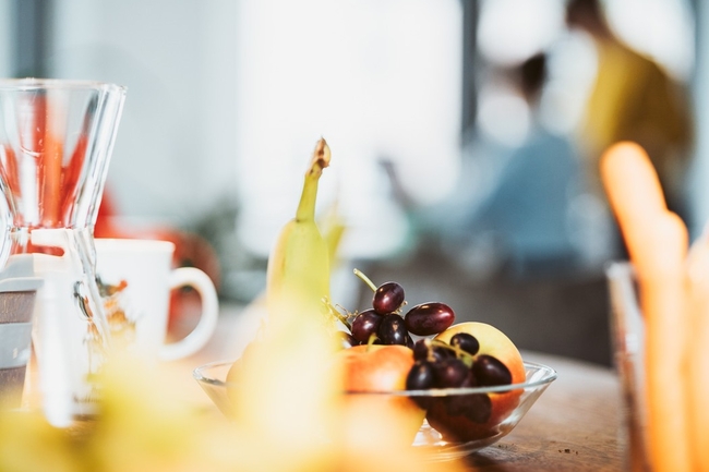 Obstkorb im Büro, dahinter Menschen
