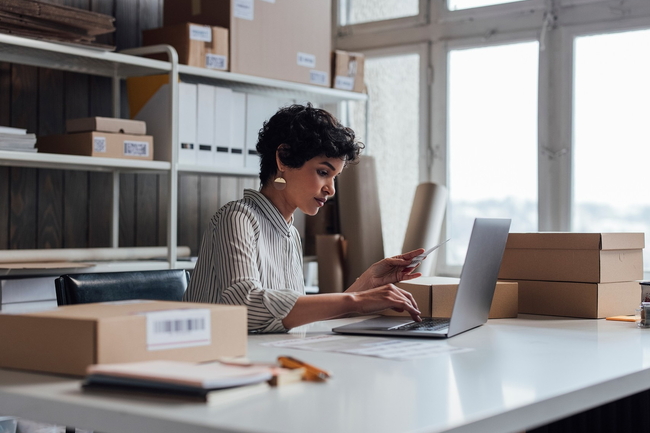 Person sitzt an einem Arbeitsplatz mit Computer und Akten