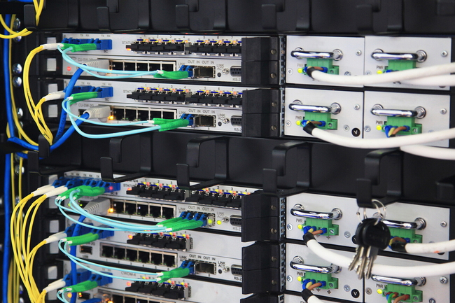 Ein Serverrack mit mehreren Netzwerkgeräten, die durch verschiedene farbige Kabel verbunden sind.