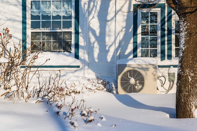Wärmepumpe vor einem Wohnhaus im Schnee
