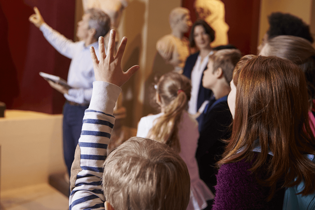 eine Mann zeigt einer Gruppe von Kindern Ausstellungsstücke in einem Museum