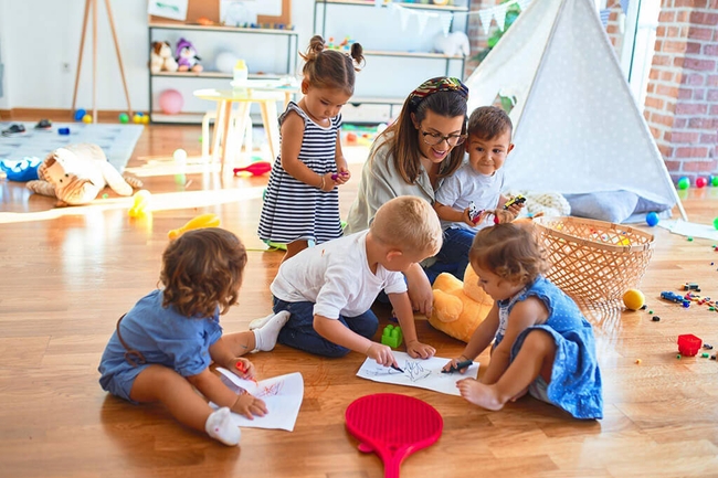 Eine Frau spielt mit mehreren Kindern in einer Kindertagesstätte