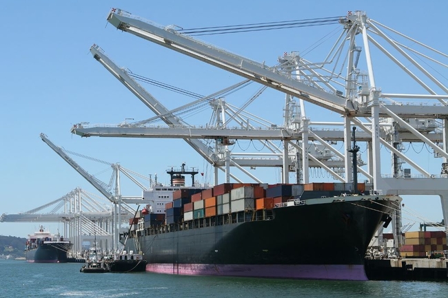 Ein großes Containerschiff wird von Kränen im Hafen mit Containern beladen.
