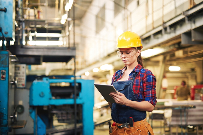 Eine Arbeiterin schaut auf ein Tablet in einer Fabrik.