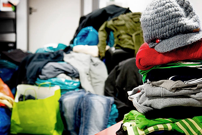 Aufgetürmte Kleiderspenden im Büro