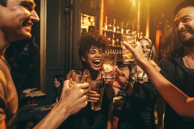 Menschen lachen ausgelassen in einer Bar und stoßen an