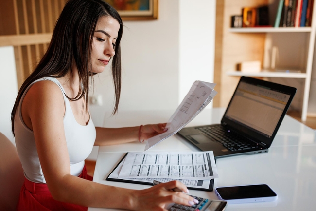 Junge Frau mit Rechnungen vor ihrem Laptop