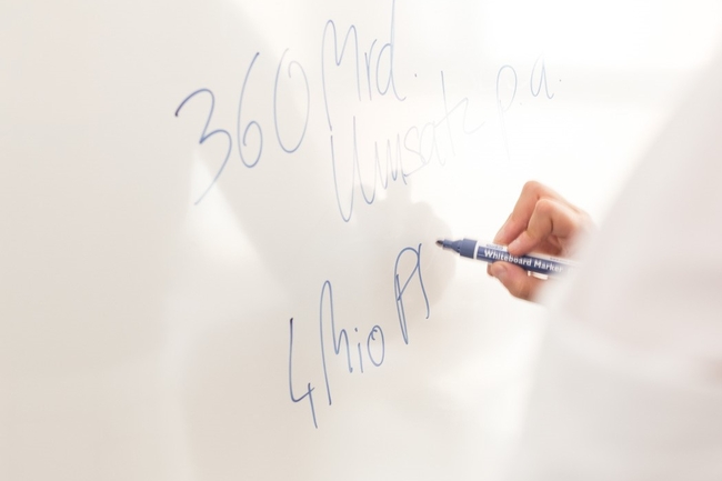 Ein Mann schreibt Umsatzzahlen auf ein Whiteboard