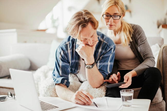 Junges Pärchen sitzt am Laptop und bespricht die Finanzen
