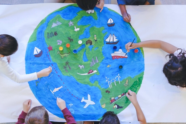 eine Gruppe von Kindern, die einen Globus mit Tieren, Fischen und Booten malen