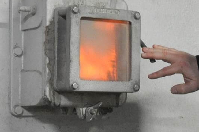 Eine Hand betätigt den Hebel einer thermischen Abfallbehandlungsanlage