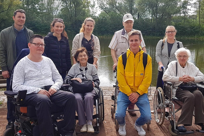 Prognos Mitarbeiterinnen und Mitarbeiter mit Bewohnern und Bewohnerinnen eines Pflegeheimes im Park