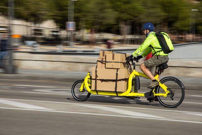 Paketzusteller fährt auf einem Elektro-Lastenrad durch die Stadt