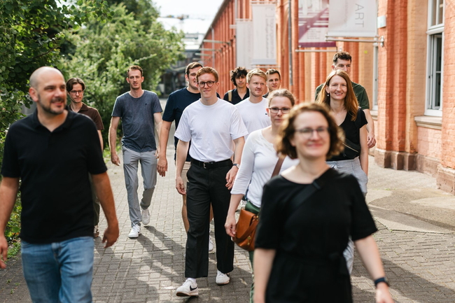 Gruppe läuft an einem Bahnhofsgebäude entlang