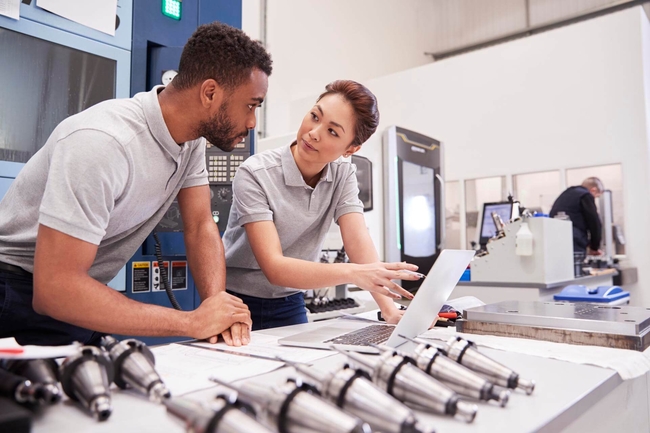 Eine Ingenieurin und ein Ingenieur arbeiten gemeinsam an einem Laptop.