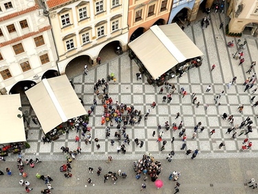 Viele Personen laufen auf einem Marktplatz. Von oben fotografiert. 