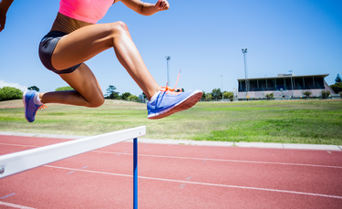 Sportlerin springt über eine Hürde