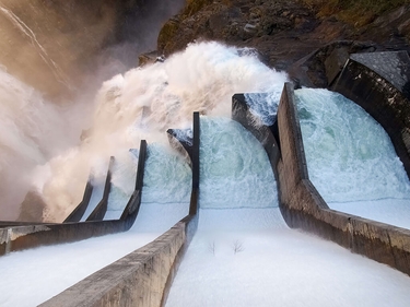 Blick von oben: Wasser fließt durch Staumauer