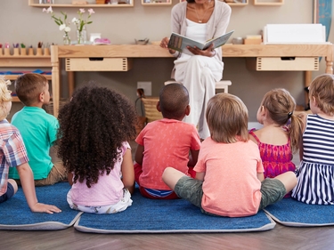 Kindergärtnerin liest Kindern ein Buch vor 