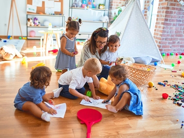 Kindergärtnerin liest Kindern ein Buch vor 