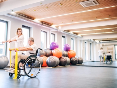 unge Frau Physiotherapeut arbeitet mit einem älteren Mann im Rollstuhl