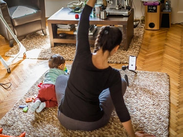 Frau mit Kind sitzt auf dem Boden und macht Sportübungen