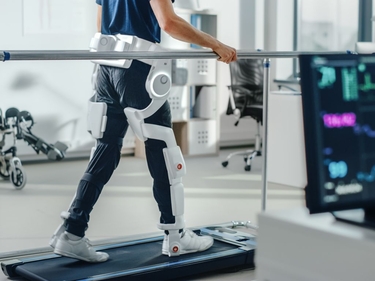 Patient mit Verletzungen geht auf dem Laufband mit fortschrittlichen Roboter-Exoskelett-Beinen