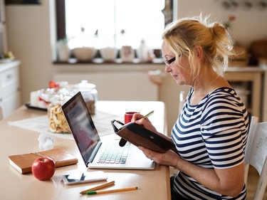 Ältere Frau mit Laptop, arbeiten am Küchentisch