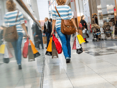 Eine Frau läuft mit vielen Einkaufstüten druch ein Shoppingscenter 