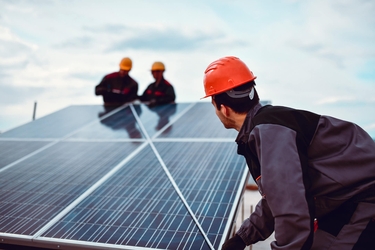 Arbeiter mit rotem Helm vermessen eine PV-Anlage 