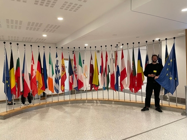 Sebastian Lübbers steht vor Fahnen im EU-Parlament