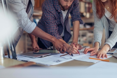 drei junge Architekten arbeiten gemeinsam an Zeichnungen