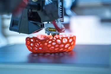 Ein 3D-Drucker druckt ein rotes Gefäß mit Löchern. 